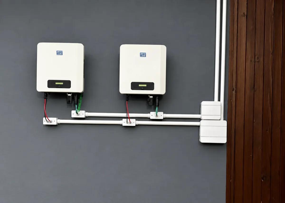 Dois inversores WEG instalados numa parede, com cabeamento em eletroduto e caixas de passagem