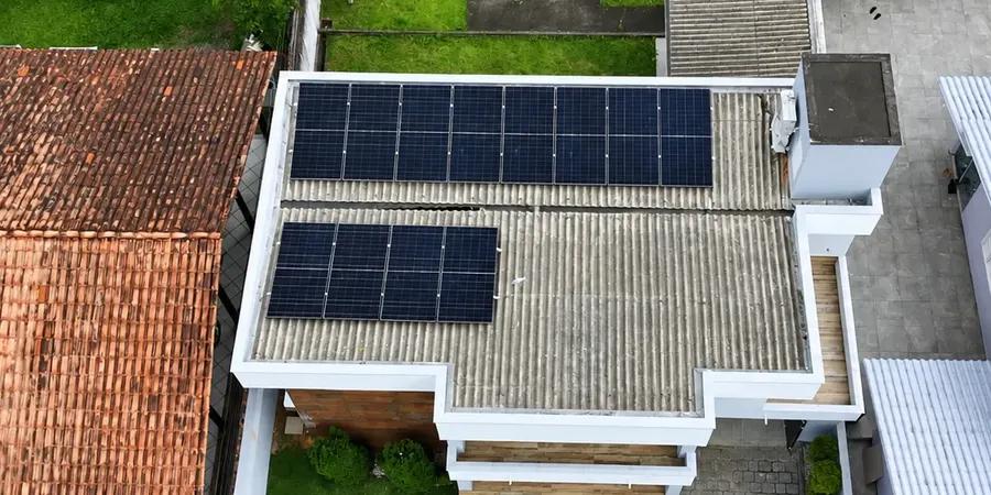 Residência em Tubarão com doze módulos solares em telhado de fibrocimento, vista de drone